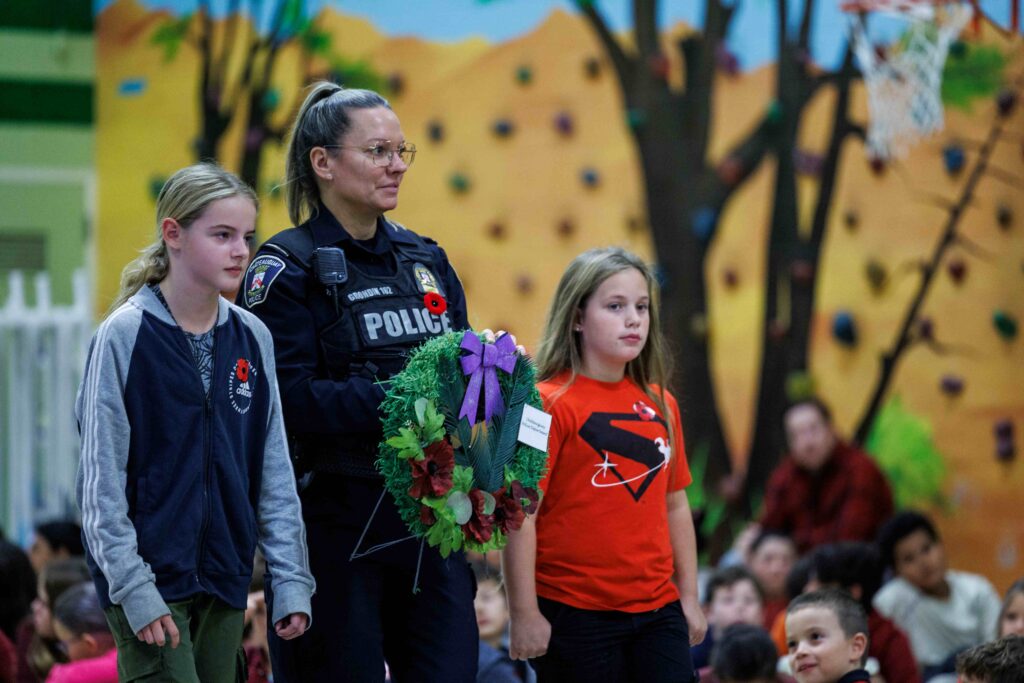 L'agente Nadia Grondin du Service de police de Châteauguay accompagnée de deux élèves à la cérémonie