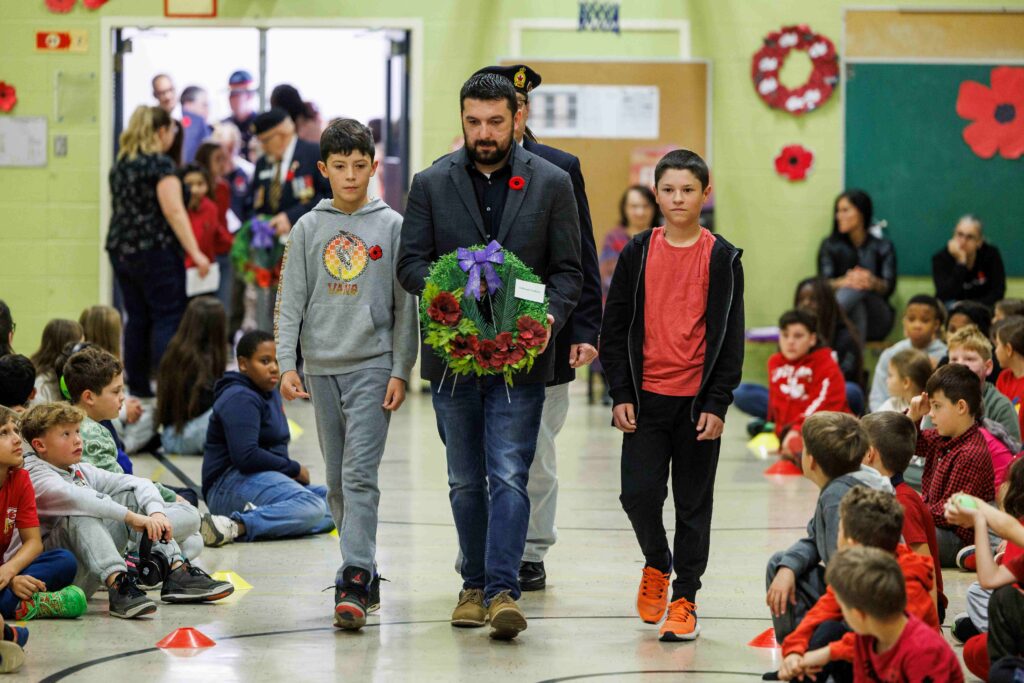 Le grand chef de Kahnawake Cody Diabo en compagnie d'élèves de l'école St-Willibrord avec une couronne de fleurs.